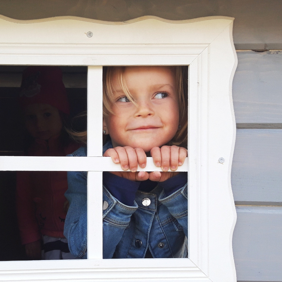 domki-ogrodowe-dla-dzieci-suski-nowotarski Dziewczynka w okienku w domku ogrodowych z drewna