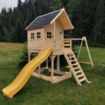 Drewniany domek ze zjeżdżalnią i huśtawkami w lesie