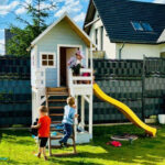 niebieski domek na podeście z żółtą zjeżdżalnią