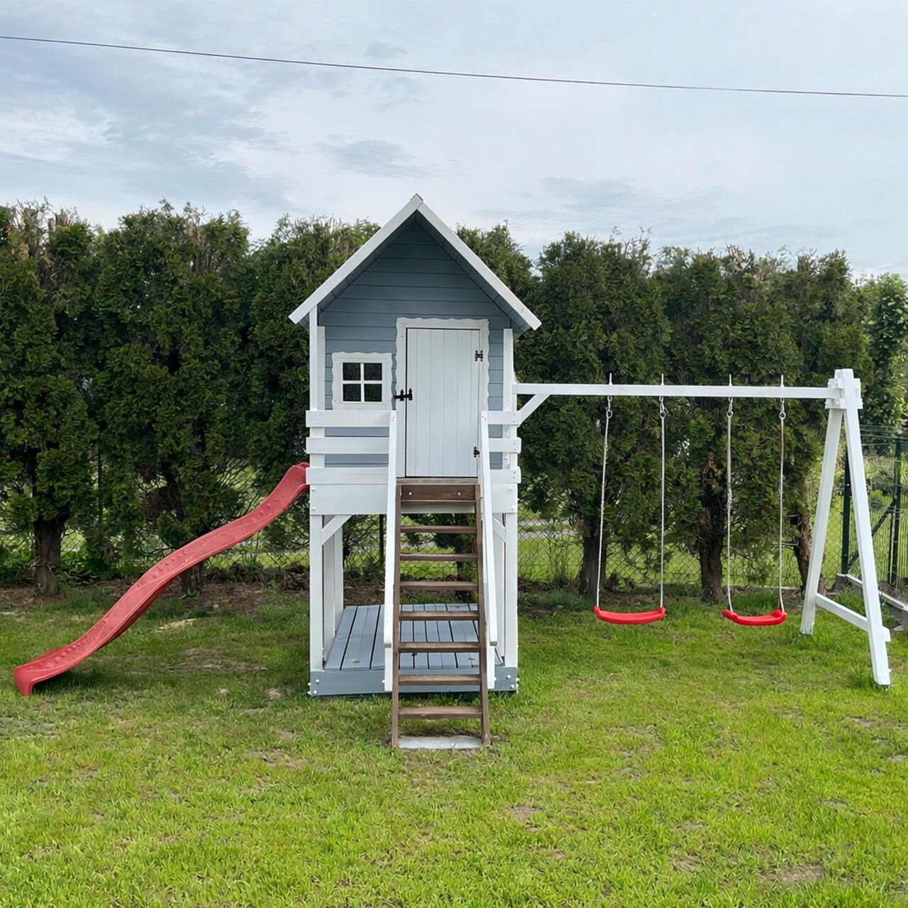 szary-domek-dla-dzieci-ze-zdjezdzalnia-hustawkami Biało szary domek na podeście dla dzieci