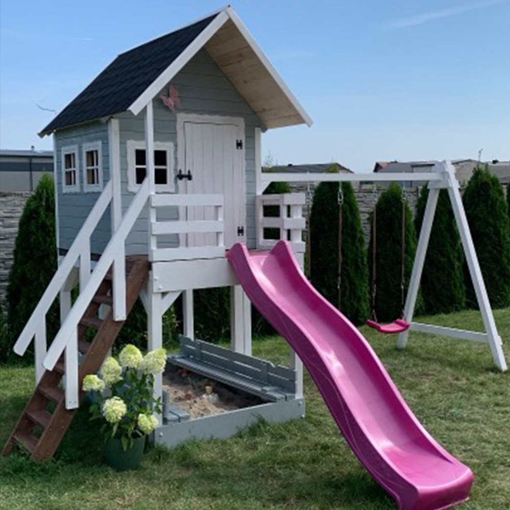 szary-domek-zjezdzalnia-rozowa-hustawki Szary drewniany domek na podeście w ogrodzie