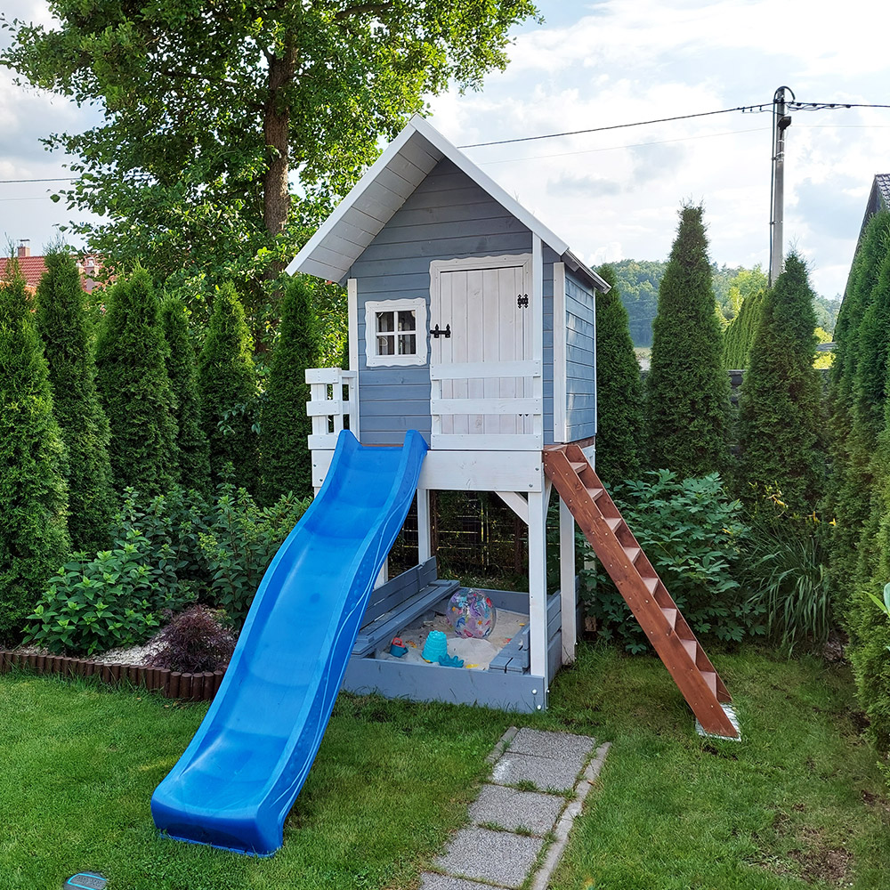 domek-dzieciecy-z-niebieska-slizgawka Szary domek na platformie z niebieską ślizgawką