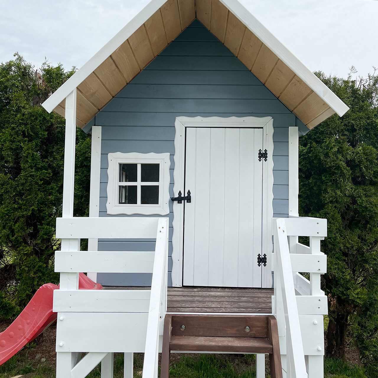 drewniany-domek-dla-dzieci-slizgawka-platforma-130 Zbliżenie na drewniany domek dla dzieci na platformie z czerwoną slizgawką